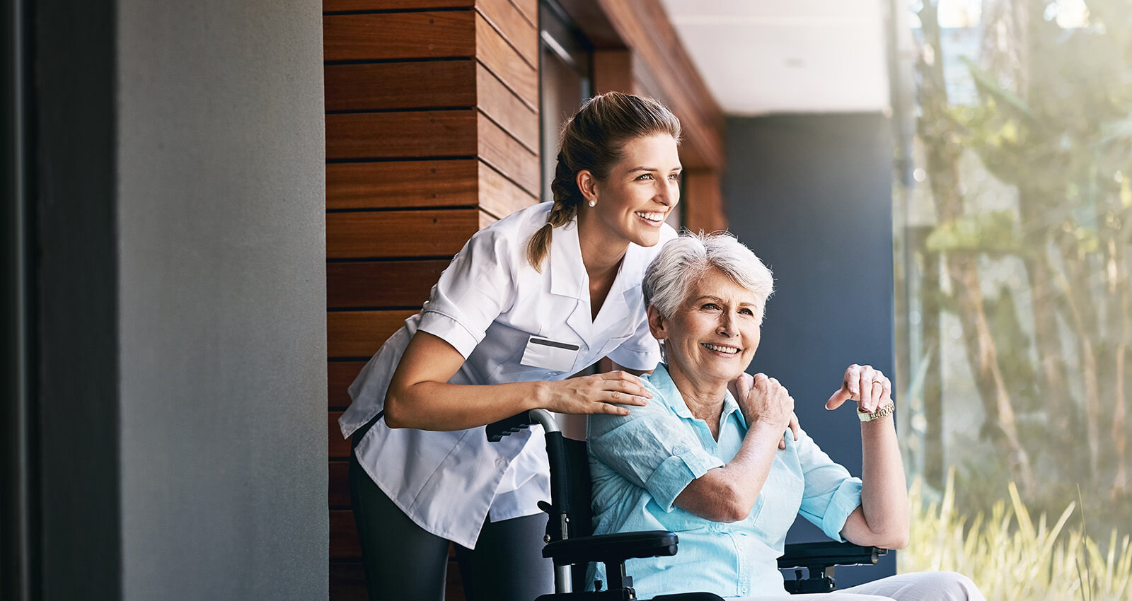Nurse standing behind senior in wheelchair